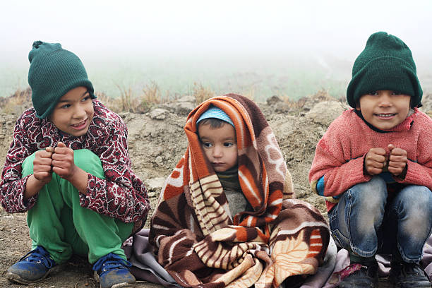 Three Poor Children Sitting in Winter Season Outdoor Portrait.